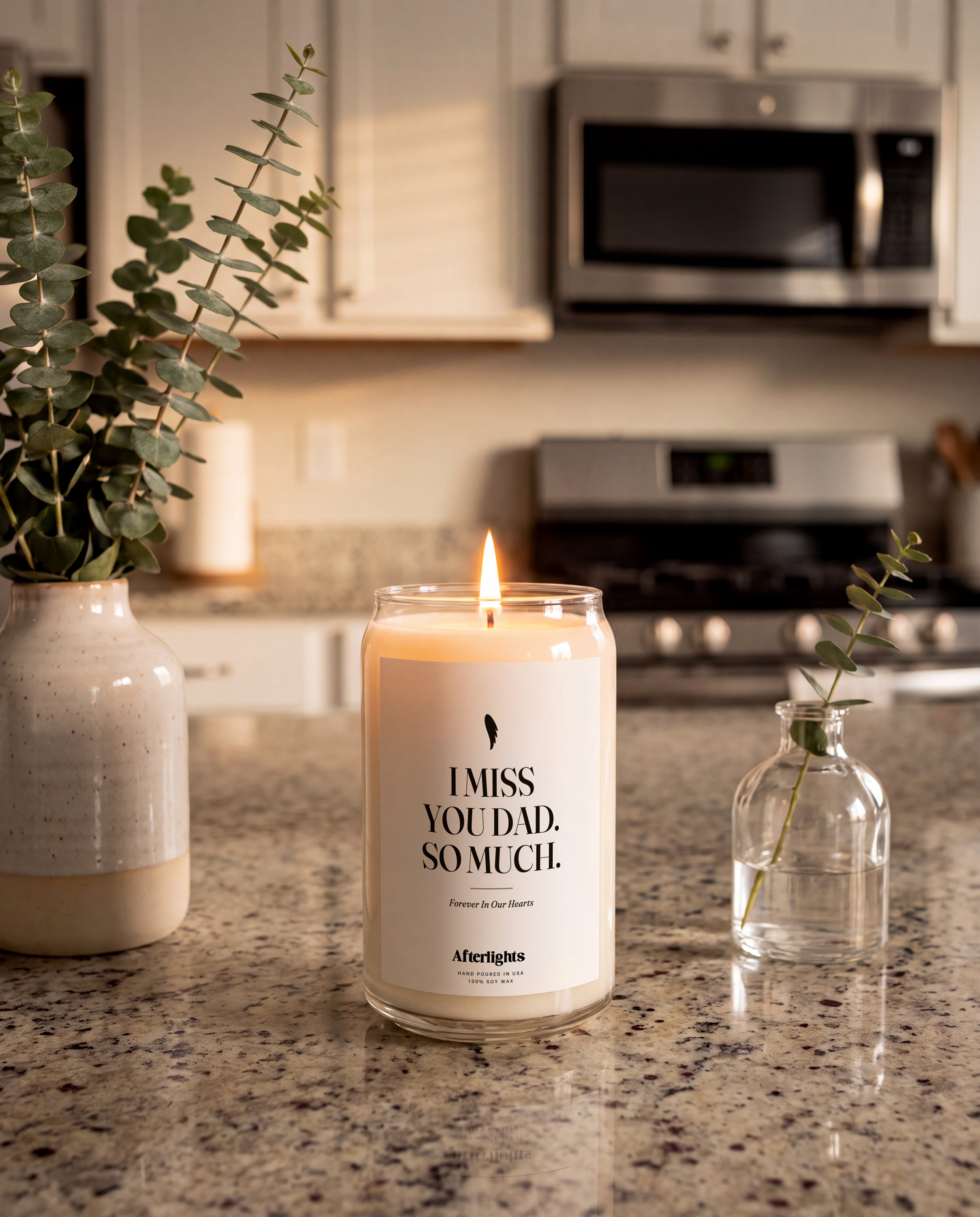 Personalized memorial candle that says I Miss You Dad, So Much, lit on a kitchen counter